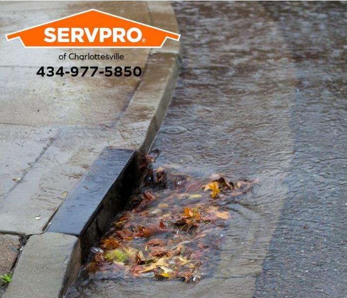 A storm drain is clogged, causing street flooding.