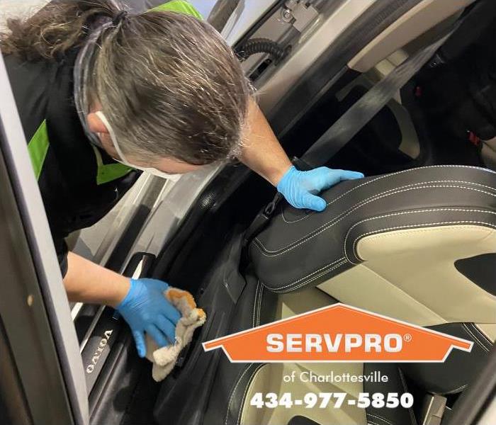 A SERVPRO professional is shown disinfecting a car.