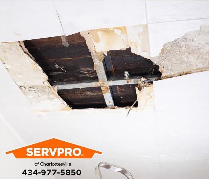 A water-damaged ceiling exposes floorboards from the floor above.